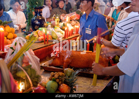 Un pellegrino offre un arrosto di maiale nella Mieu Ba Chua Xu, Nui Sam durante il Tet, sperando in una buona fortuna e prosperità per il nuovo anno Foto Stock