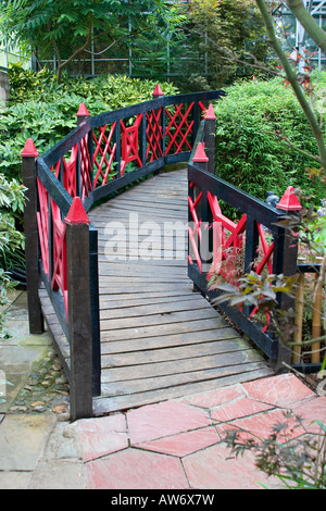 Rosso e nero dipinto di ponte di legno in un giardino in stile giapponese Foto Stock