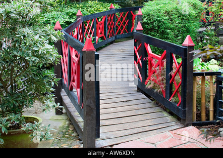 Rosso e nero dipinto di ponte di legno in un giardino in stile giapponese Foto Stock