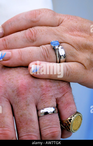 Chiudere fino alle mani di una coppia di novelli sposi toccando le mani teneramente e mostrando le loro fedi Foto Stock