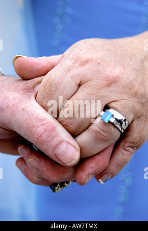 Chiudere fino alle mani di una coppia di novelli sposi tenendo le mani teneramente e mostra il suo anello di nozze Foto Stock
