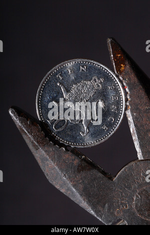 British denaro 10p 10 pence coin essendo mantenuto spremere dalla pinza finanziaria il concetto di pressione Foto Stock