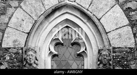 Dettagli architettonici close up di una ad arco gotico la finestra della chiesa con facce di pietra di ciascun lato e chiaro vetro piombato in panoramica Foto Stock