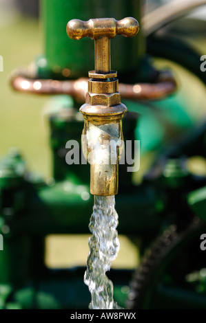 Un rubinetto esterno in un giardino in esecuzione con acqua fresca acceso per innaffiare le piante del giardino da un rubinetto in ottone Foto Stock