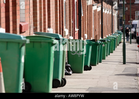 Una fila di verde raccoglitori di rifiuti in attesa di essere raccolti su un marciapiede in Nottingham, Regno Unito Foto Stock