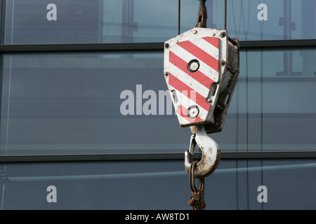 Paesaggio shot del rosso e del bianco blocco del gancio della gru contro la moderna in vetro facciata di office Foto Stock