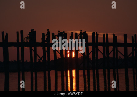 I monaci e gli abitanti di un villaggio di casa a piedi al tramonto attraverso U Bein's Bridge Amarapura, Myanmar (Birmania) Foto Stock