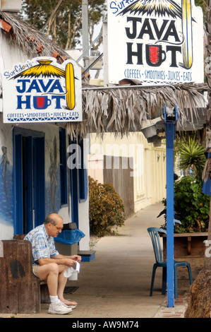 Un uomo mette le sue scarpe e calzini all'esterno di un bar a Encinitas, California, USA Foto Stock