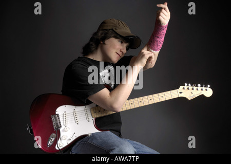 Teenage con un braccio rotto a suonare la chitarra Foto Stock