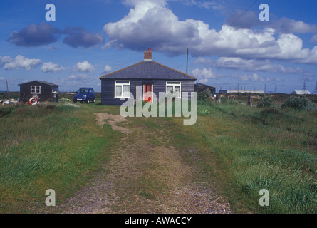 Bungalow nero a Dungeness, nei pressi della stazione di potenza con energia elettrica tralicci in orizzontale Foto Stock