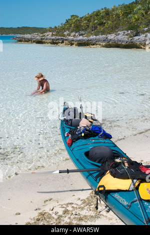 Un uomo si prende una pausa dal kayak di mare e pesca con la mosca di sedersi nelle acque tropicali nelle isole Exuma, Bahamas. Foto Stock