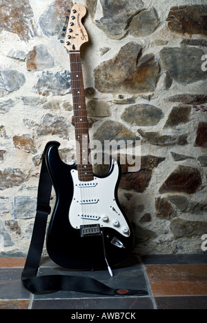 Immagine di un bianco e nero chitarra elettrica appoggiata contro una parete Foto Stock