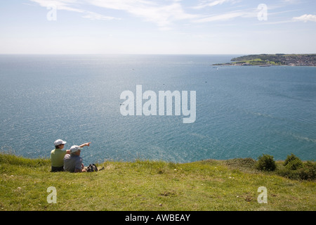 Giovane seduto sulla scogliera che affaccia sulla baia di Swanage Dorset Regno Unito Foto Stock