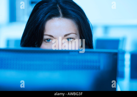 Woman in office looking at computer screen Foto Stock