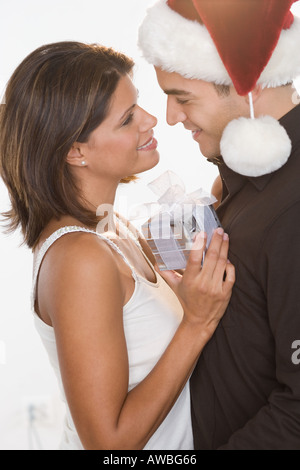 Uomo in Santa hat dando dono alla donna Foto Stock