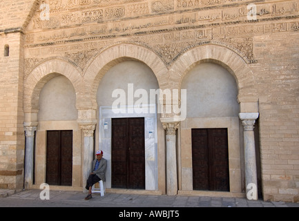 Un vecchio uomo seduto vicino all'ingresso del cosiddetto 'porta tre' moschea di Kairouan, Tunisia Foto Stock