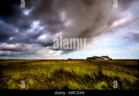 Strada di ciottoli Suffolk - minacciose nuvole temporalesche incombente su una casa sulla spiaggia spazzate dal vento a Shingle Street, Suffolk. Regno Unito meteo. Foto Stock