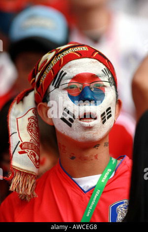 Una ventola coreano indossare occhiali o una visiera di vernice canta in mezzo alla folla durante la Coppa del Mondo 2006 Foto Stock