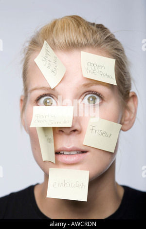 Giovane donna con molti Post-it in faccia Foto Stock