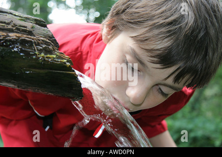 Giovane ragazzo beve l'acqua da un pozzo Foto Stock