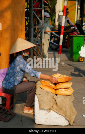 Donna baguette di vendita nelle stradine del centro storico di Hanoi Foto Stock