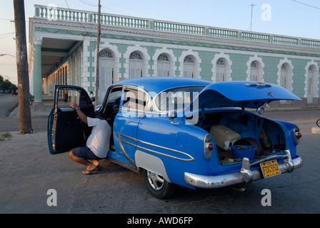 Auto d'epoca, sottoposti a riparazioni, il suo cofano sollevato, a fronte di un'era coloniale edificio a Cienfuegos, Cuba, Americhe Foto Stock