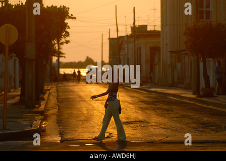 Donna che cammina su una strada al tramonto a Cienfuegos, Cuba, Americhe Foto Stock