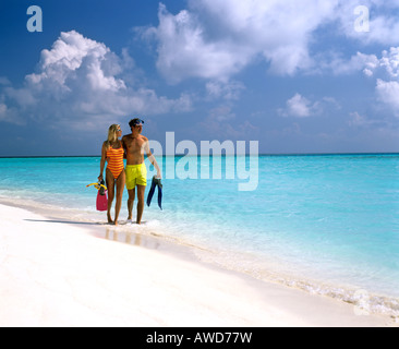 Coppia giovane con snorkeling a piedi in acqua poco profonda, spiaggia sabbiosa, Maldive, Oceano Indiano Foto Stock