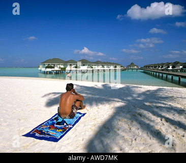 Giovane uomo sulla spiaggia, acqua bungalows su Paradise Island, Lakanfinolhu, North Male Atoll, Maldive, Oceano Indiano Foto Stock