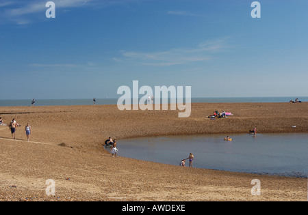 La gente di balneazione e passeggiate in un ingresso di acqua al vecchio Felixtowe Beach in una bella giornata d'estate Foto Stock