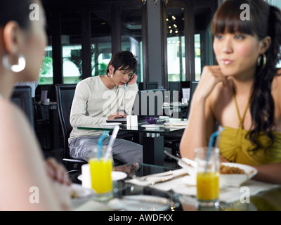 Giovani donne in chat, uomo su laptop come sfondo Foto Stock