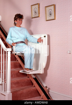 Età media di età della donna femmina utilizzando scale sedia ascensore in home handicap spazio di copia Foto Stock