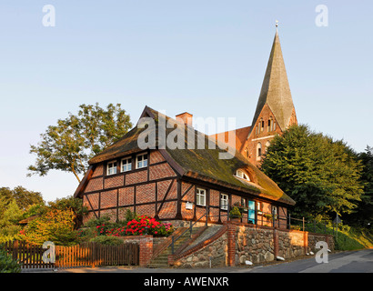 Casa in stile Fachwerk con tetto in paglia con chiesa sullo sfondo, Gustow, Ruegen, Germania, Europa Foto Stock