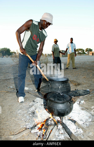 Gli uomini la cottura nella piazza del villaggio, Sehitwa, Botswana, Africa Foto Stock