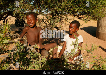 Due ragazzi seesawing su un ramo, Cattlepost Bothatogo, Botswana, Africa Foto Stock