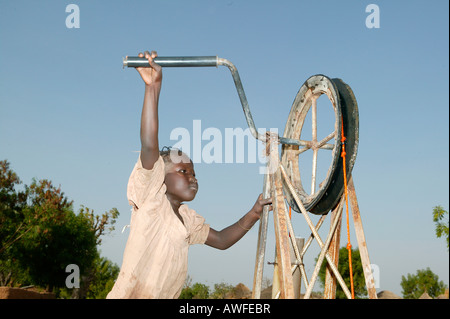 Ragazzo il recupero di acqua da un pozzo, Camerun, Africa Foto Stock