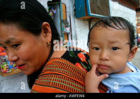 La madre che porta il suo figlio sulle sue spalle, Bhutan Foto Stock