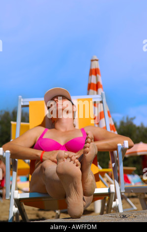 Donna godendo il sole sulla spiaggia, Caorle, Veneto, Italia Foto Stock