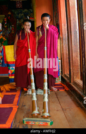 Due monaci giocare i loro tradizionali tromba, Bhutan Foto Stock