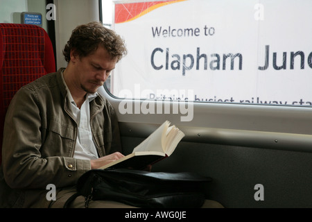 Uomo libro lettura mentre il treno attende a Clapham Junction Foto Stock