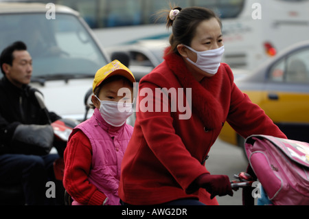 Madre e figlia che indossa la maschera mentre bike a scuola a Pechino, uno dei più aria inquinata città in tutto il mondo.12-Mar-2008 Foto Stock