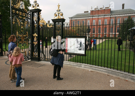 I turisti di leggere informazioni su una principessa Diana Memorial mostra sulle porte di Kensington Palace Hyde Park Londra Inghilterra UK UE Foto Stock