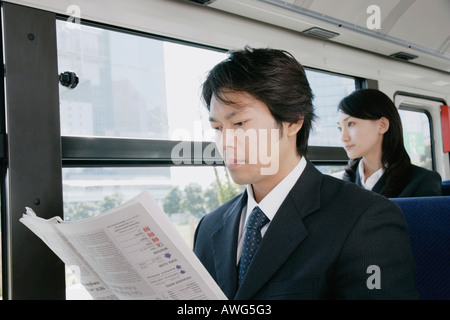 Una metà uomo adulto leggendo il giornale in un bus Foto Stock