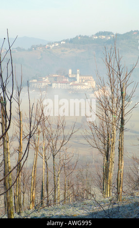 Una vecchia fattoria e attraverso la nebbia emerge la città di Monterchi sul confine tra Toscana e Umbria Italia Foto Stock