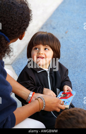 Bambina ottiene aiuto da adulto presso il centro diurno. Foto Stock