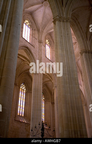 Alte colonne e le finestre di vetro macchiate all'interno dell'ornato il Monastero di Batalha Portogallo Foto Stock