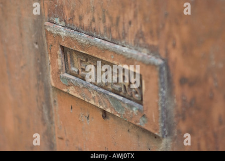 Vecchio arrugginito letterbox su una porta invecchiato Foto Stock