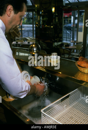 L'uomo lavaggio bicchieri in cafe Foto Stock