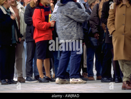 La folla di persone in piedi in linea sul marciapiede, vista ritagliata Foto Stock