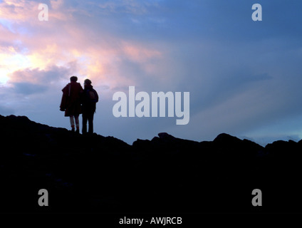 Due persone in piedi sulla montagna rocciosa, silhouette Foto Stock